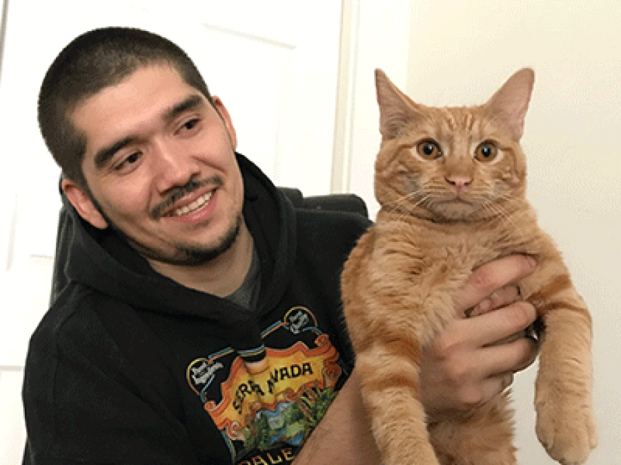 Jorge holds up his cat, Buddy, ready for their picture